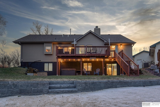 back house at dusk featuring a wooden deck and a hot tub