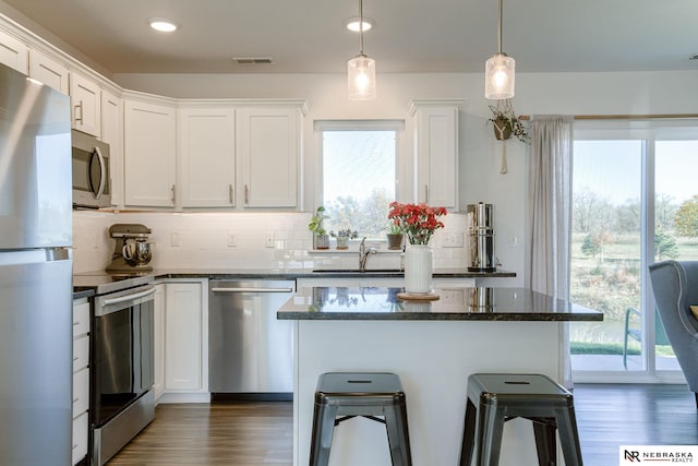 kitchen featuring decorative light fixtures, white cabinets, appliances with stainless steel finishes, and sink