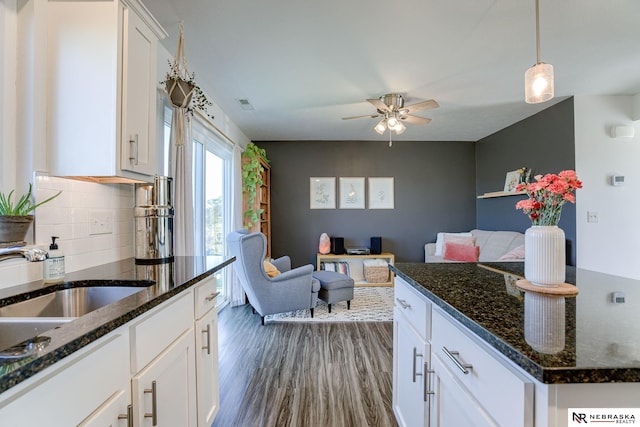 kitchen featuring white cabinets, hanging light fixtures, dark stone countertops, and decorative backsplash