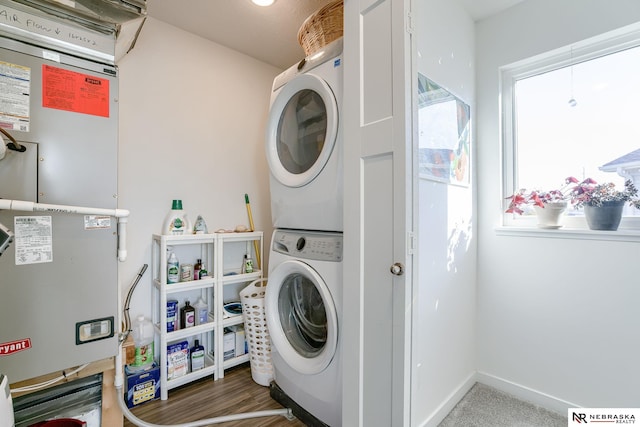 laundry room with stacked washer and clothes dryer, heating unit, and dark wood-type flooring