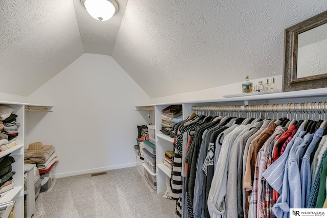 spacious closet featuring vaulted ceiling and light colored carpet