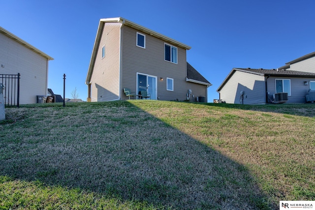 rear view of house with cooling unit and a lawn