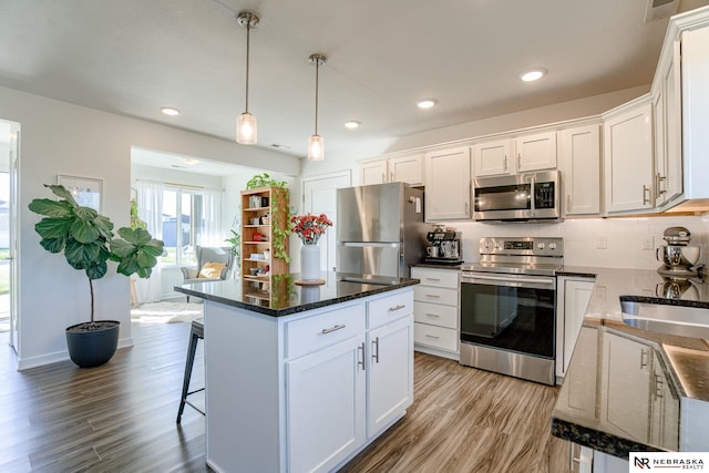 kitchen featuring light hardwood / wood-style floors, stainless steel appliances, white cabinetry, and backsplash