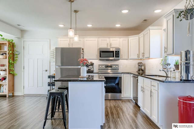 kitchen with sink, white cabinetry, hanging light fixtures, and appliances with stainless steel finishes