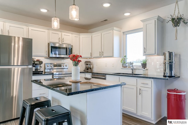 kitchen featuring stainless steel appliances, white cabinetry, hanging light fixtures, and sink