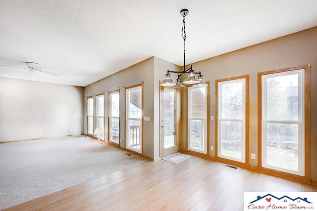 unfurnished room with light carpet and ceiling fan with notable chandelier