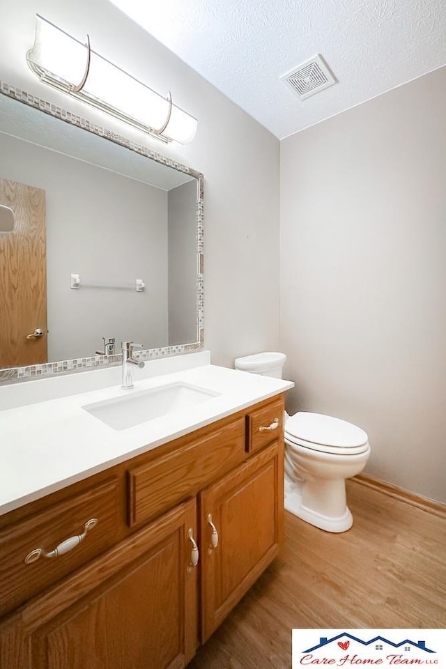 bathroom with hardwood / wood-style floors, vanity, a textured ceiling, and toilet