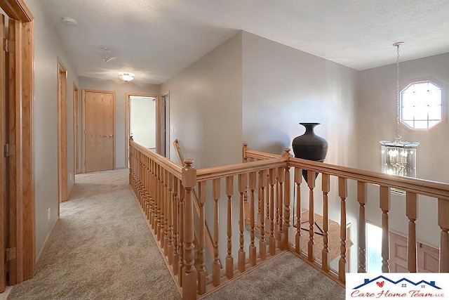 hall with a chandelier and light colored carpet