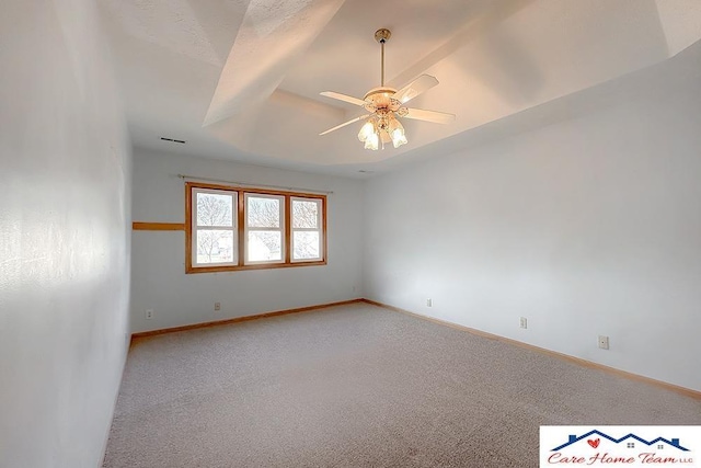 unfurnished room featuring carpet floors, a tray ceiling, and ceiling fan