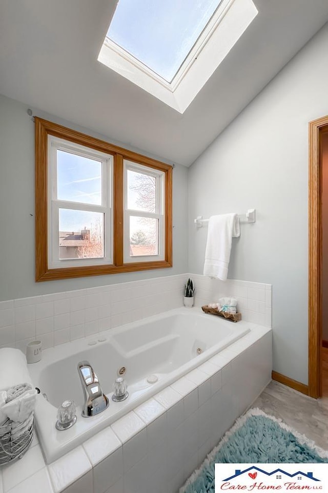 bathroom with tile patterned flooring, tiled bath, and vaulted ceiling with skylight