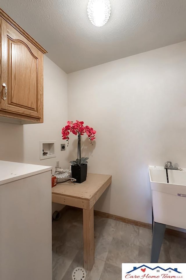 laundry area with cabinets, hookup for a washing machine, hookup for an electric dryer, a textured ceiling, and sink