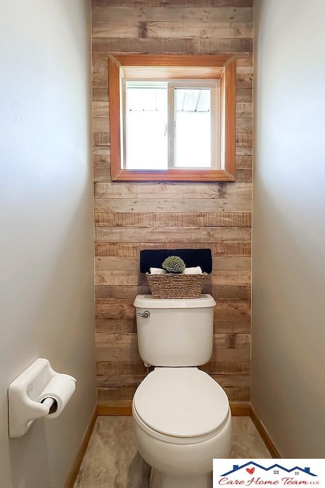 bathroom featuring toilet and wooden walls