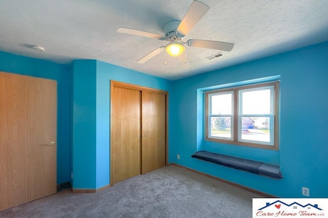 unfurnished bedroom with a textured ceiling, carpet floors, a closet, and ceiling fan