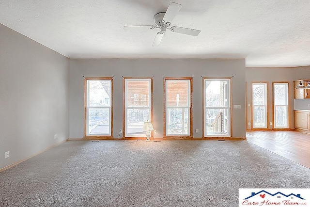 spare room featuring ceiling fan, light carpet, and a textured ceiling