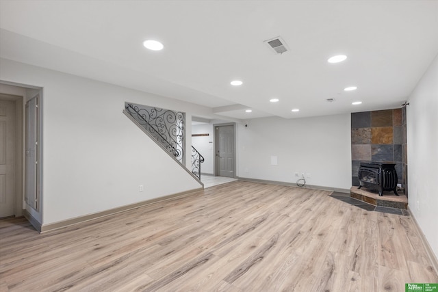 unfurnished living room with a wood stove and light hardwood / wood-style flooring