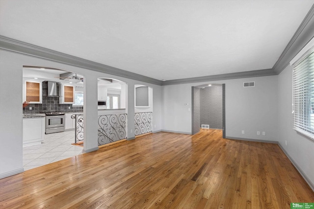 unfurnished living room with light hardwood / wood-style floors, plenty of natural light, and ornamental molding