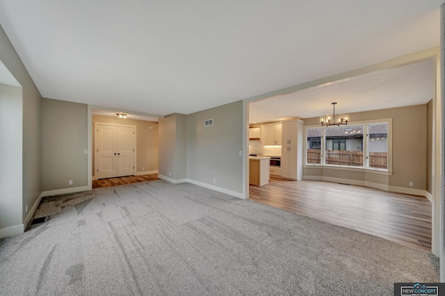 unfurnished living room featuring light carpet and a chandelier