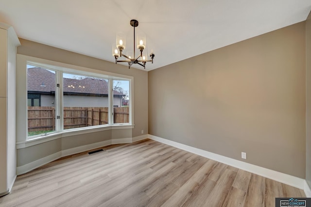 unfurnished dining area featuring a notable chandelier, a healthy amount of sunlight, and light hardwood / wood-style flooring