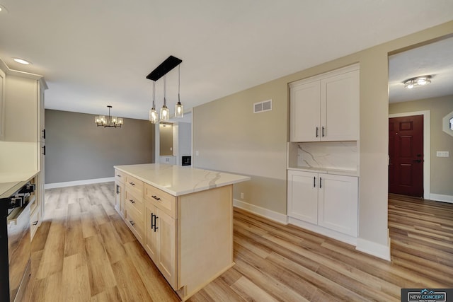 kitchen with a notable chandelier, a center island, hanging light fixtures, and light hardwood / wood-style flooring