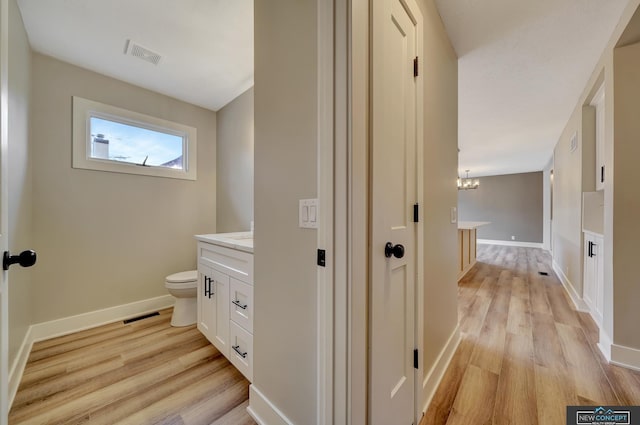 bathroom featuring hardwood / wood-style floors, vanity, toilet, and a chandelier