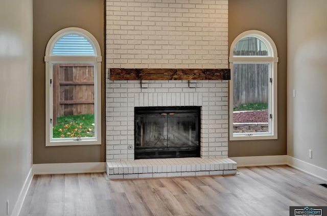 unfurnished living room featuring a fireplace, a wealth of natural light, and light hardwood / wood-style flooring