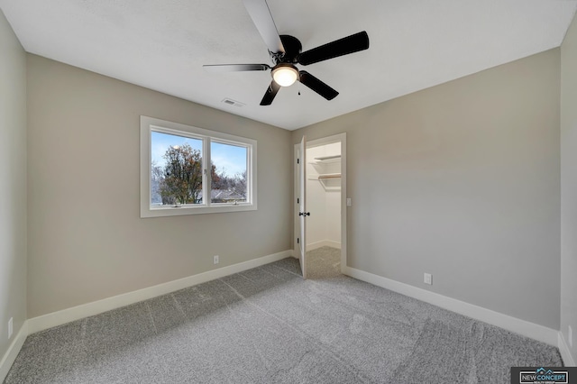 unfurnished bedroom with carpet, ceiling fan, a walk in closet, and a closet