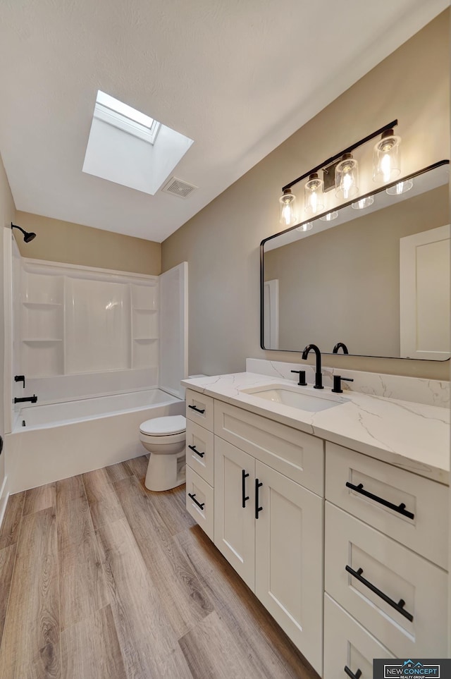 full bathroom featuring vanity, shower / washtub combination, a skylight, toilet, and wood-type flooring