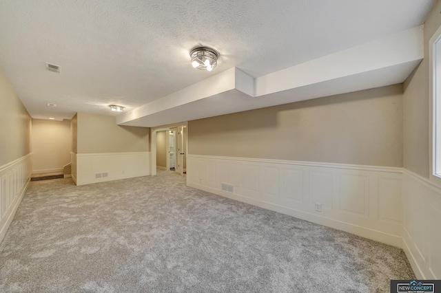 basement featuring carpet flooring and a textured ceiling