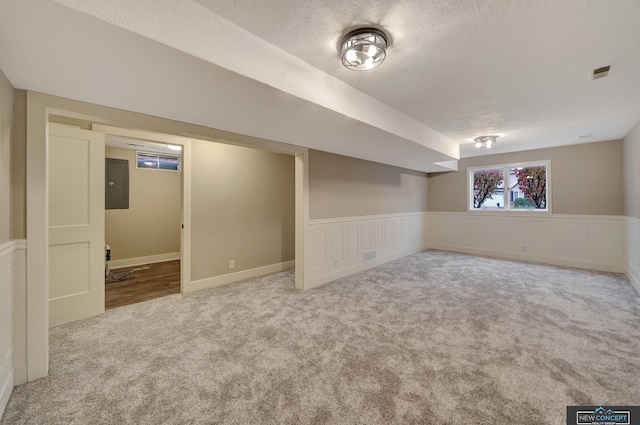 basement with carpet, a textured ceiling, and electric panel