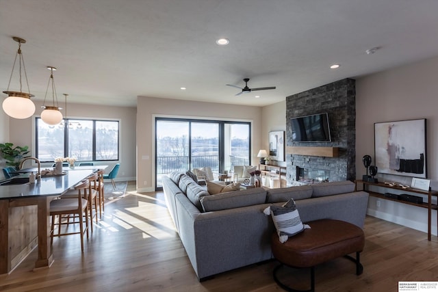 living room with a fireplace, wood-type flooring, ceiling fan, and sink