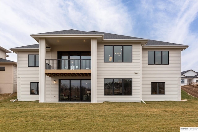 rear view of house with a yard and a balcony