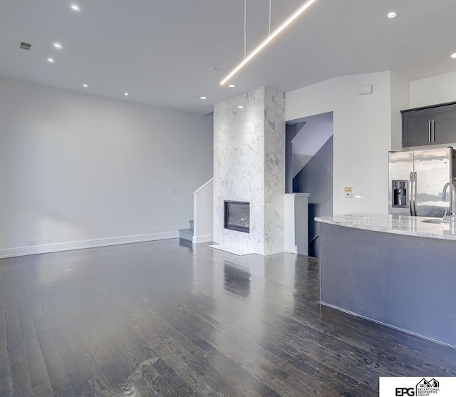 unfurnished living room featuring a fireplace, dark hardwood / wood-style floors, and sink