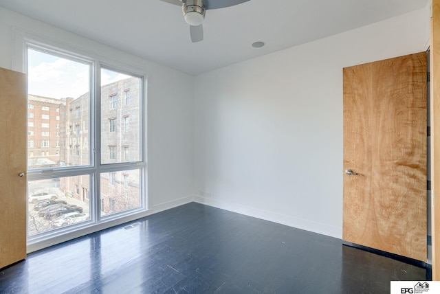 empty room with ceiling fan and dark wood-type flooring