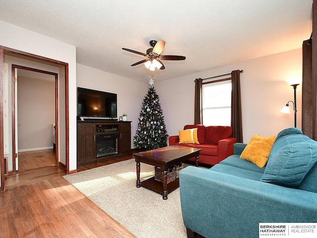 living room with ceiling fan, hardwood / wood-style floors, and a textured ceiling