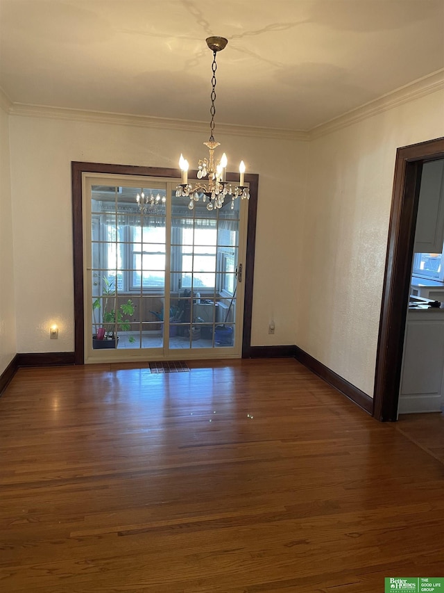 unfurnished dining area with dark hardwood / wood-style floors, crown molding, and a chandelier