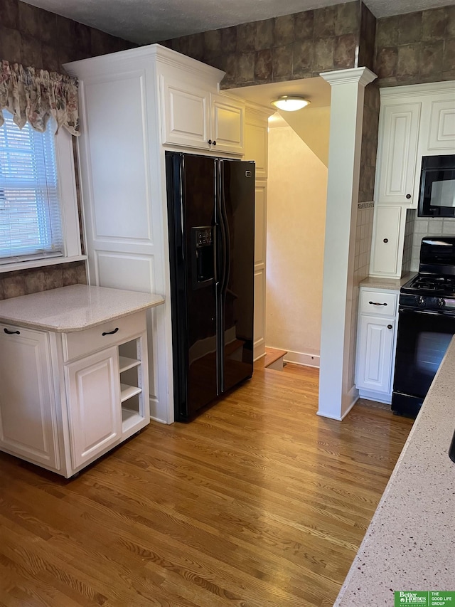 kitchen featuring hardwood / wood-style flooring, backsplash, white cabinets, and black appliances