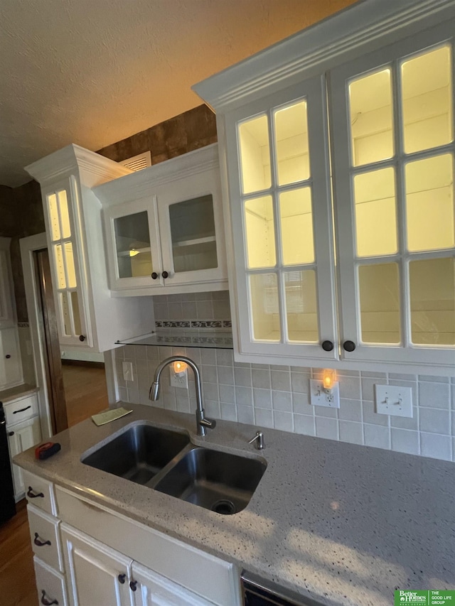 kitchen featuring light stone countertops, sink, white cabinetry, and decorative backsplash