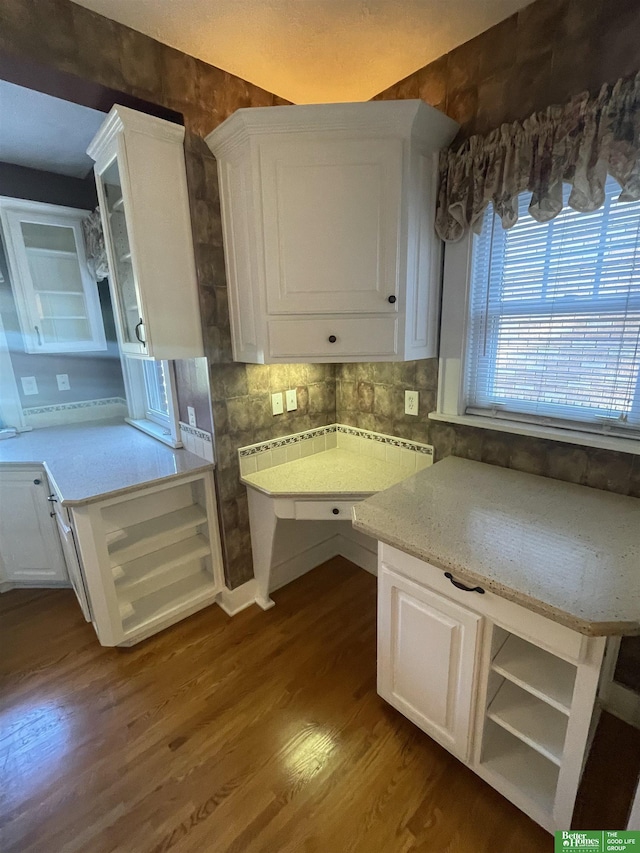 kitchen with decorative backsplash, light stone countertops, white cabinetry, and dark hardwood / wood-style flooring