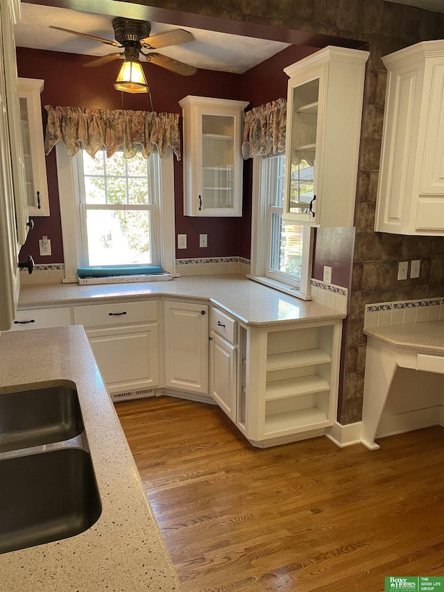 kitchen with ceiling fan, sink, light hardwood / wood-style flooring, light stone countertops, and white cabinets