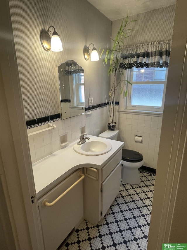 bathroom with toilet, tile walls, and vanity