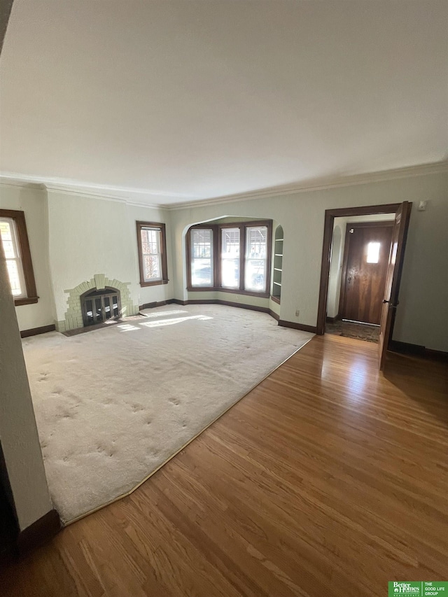 unfurnished living room with ornamental molding and hardwood / wood-style floors