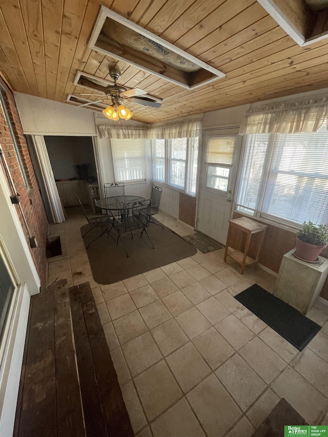 unfurnished sunroom with ceiling fan, wooden ceiling, and a wealth of natural light