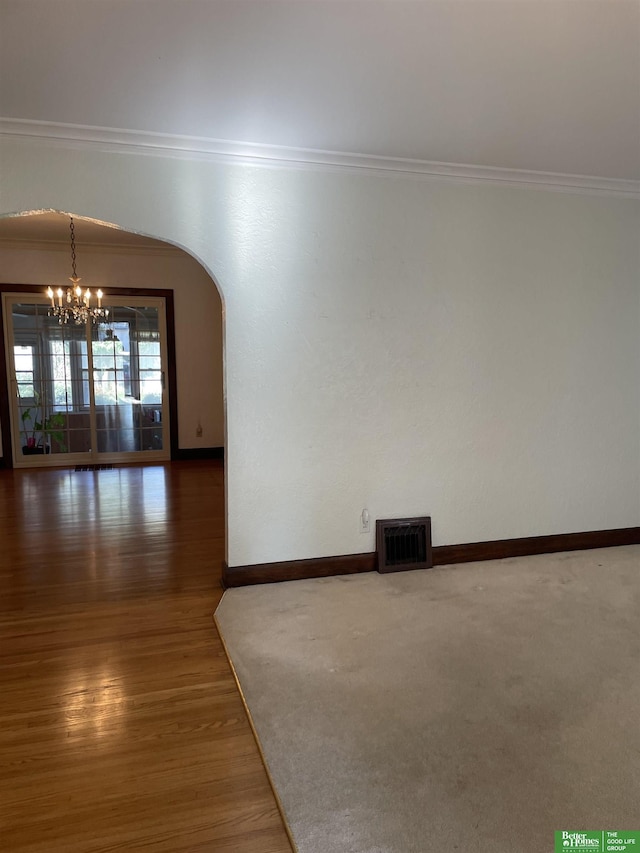 unfurnished room with dark hardwood / wood-style flooring, crown molding, and a notable chandelier