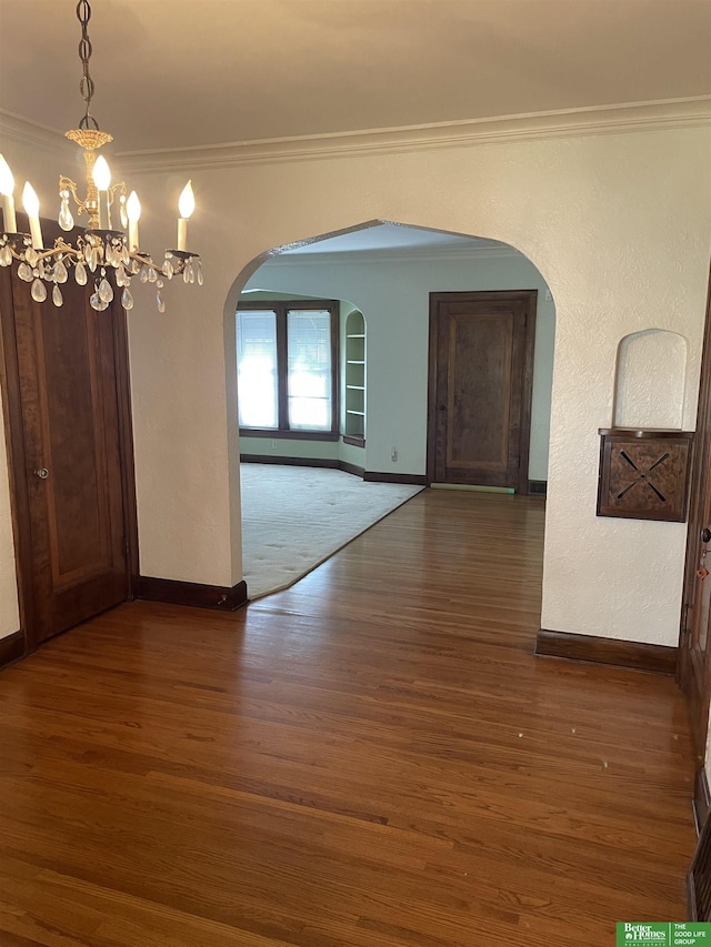 unfurnished dining area featuring an inviting chandelier, ornamental molding, and dark hardwood / wood-style flooring