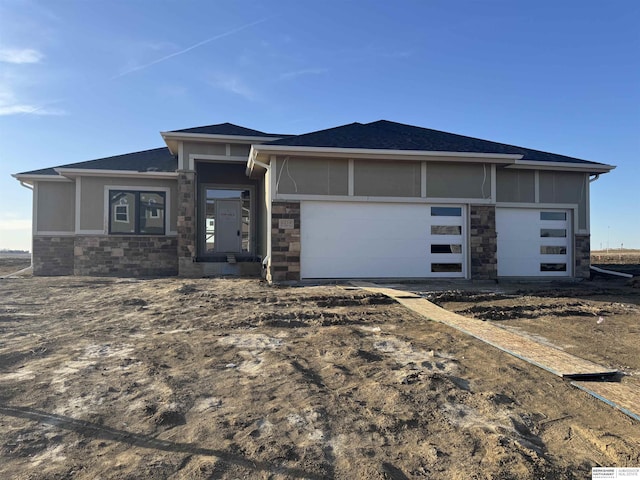 prairie-style home with stone siding and a garage