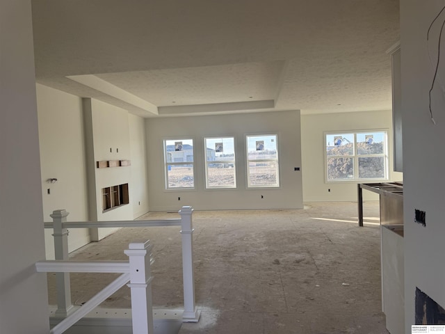 unfurnished living room with a fireplace, a textured ceiling, and a raised ceiling