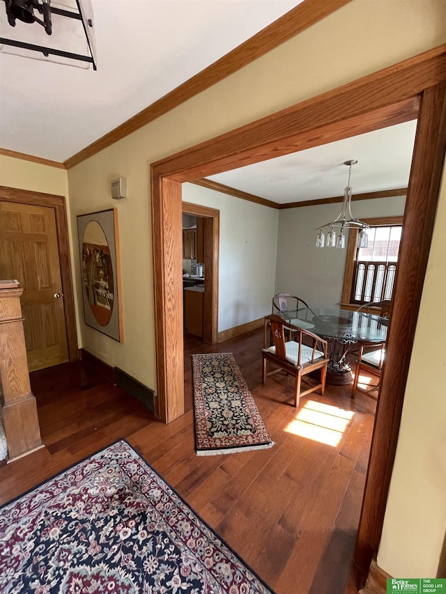 dining space with dark hardwood / wood-style floors, ornamental molding, and a notable chandelier