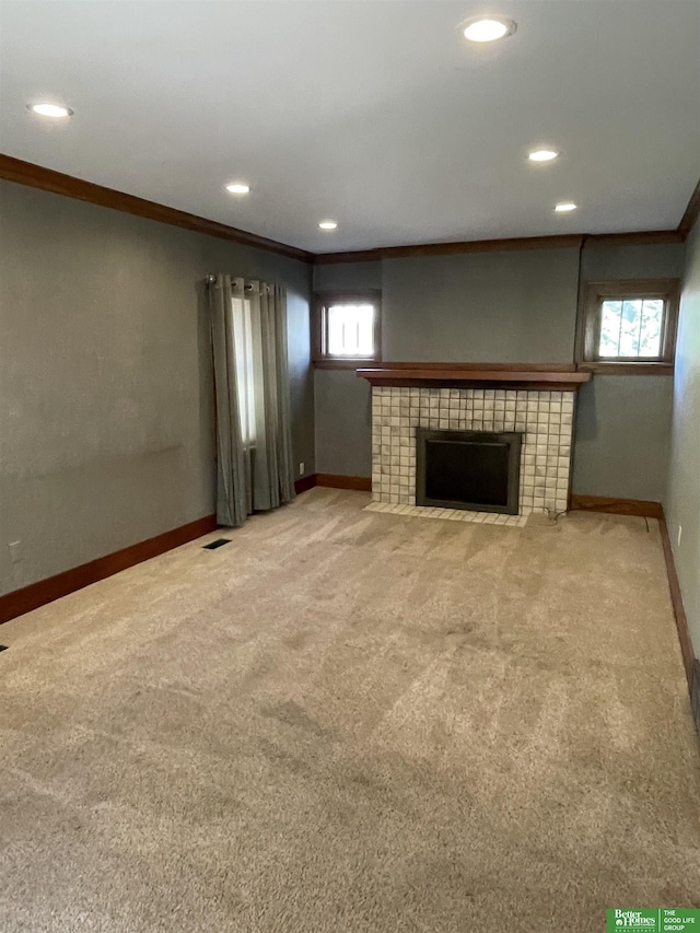 unfurnished living room with carpet, crown molding, and a tile fireplace