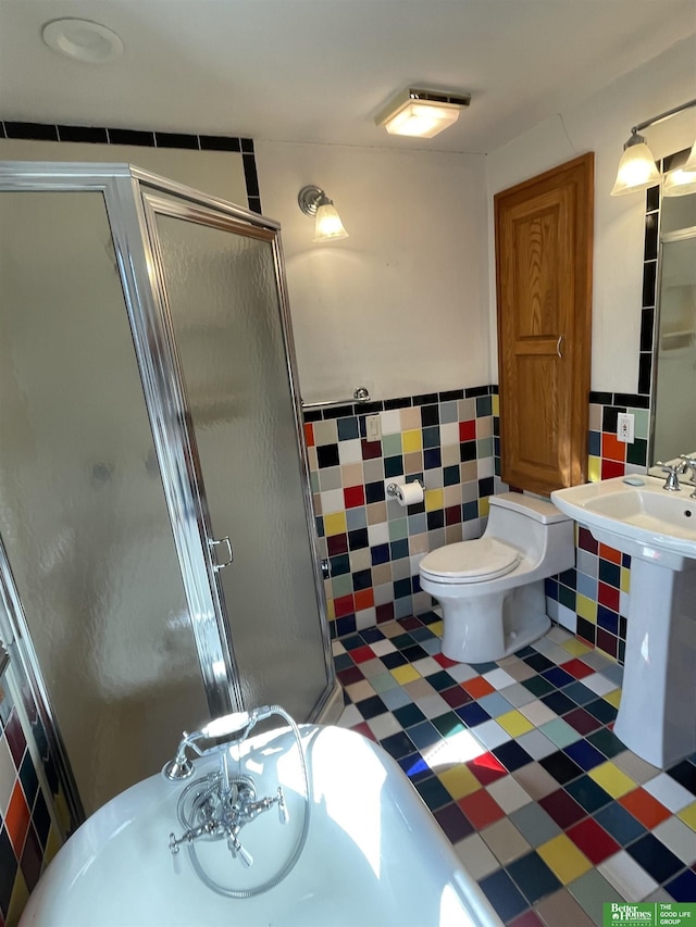 bathroom with toilet, a shower with shower door, and tile walls