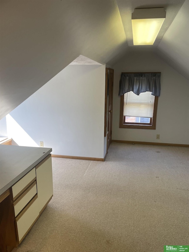 additional living space featuring light colored carpet and vaulted ceiling